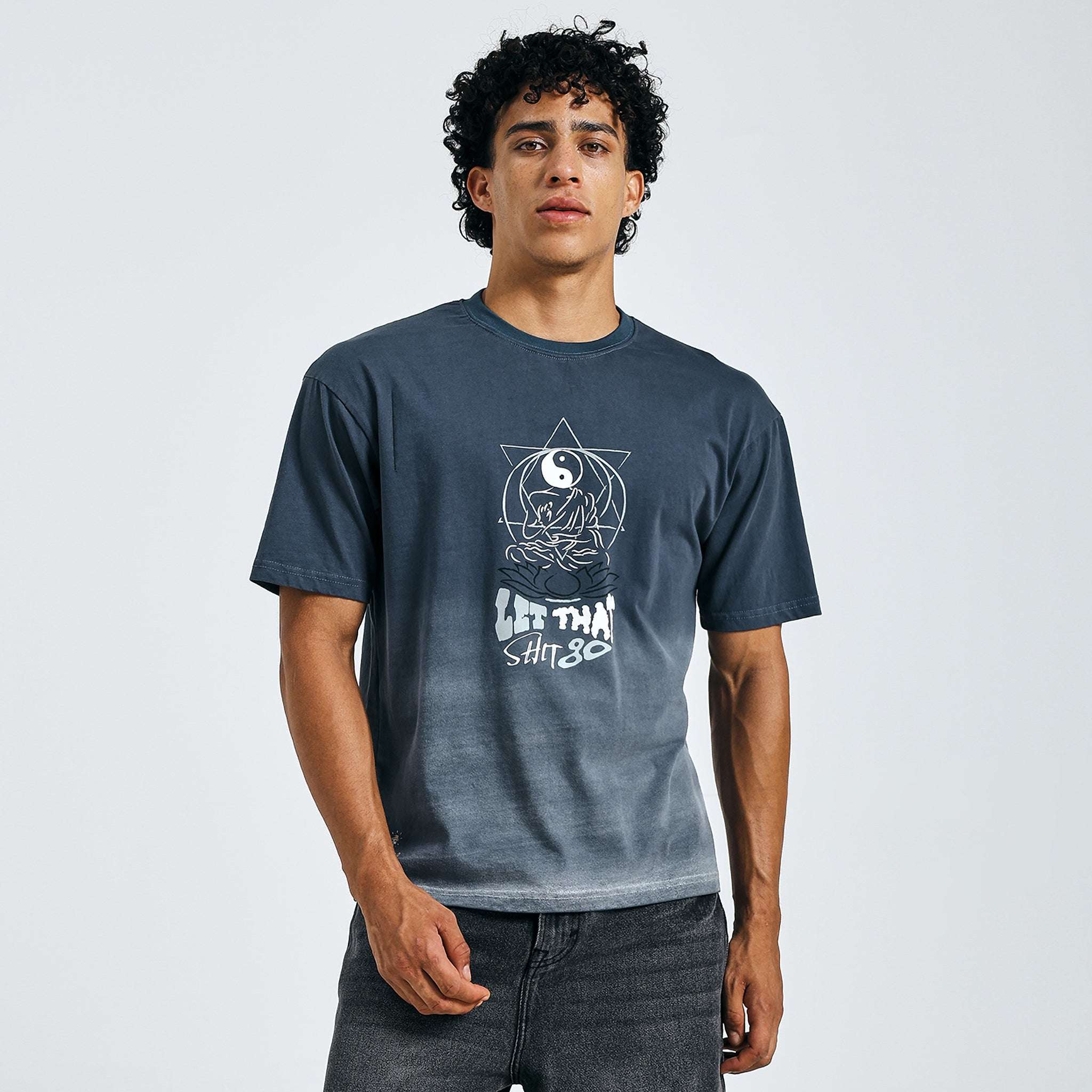 Person wearing a blue t-shirt with a graphic design on a plain background