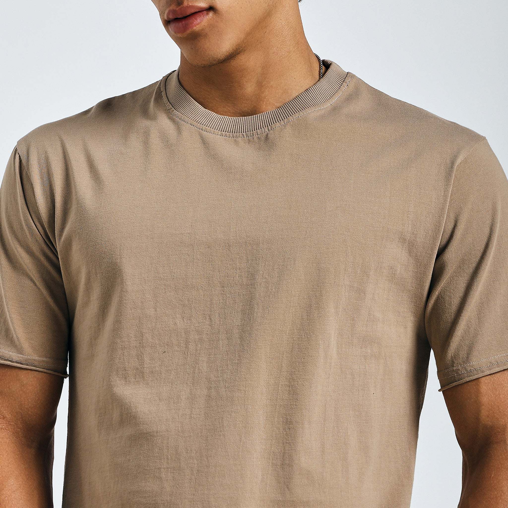 Close-up of beige minimalist graphic tee with raw edges and hem