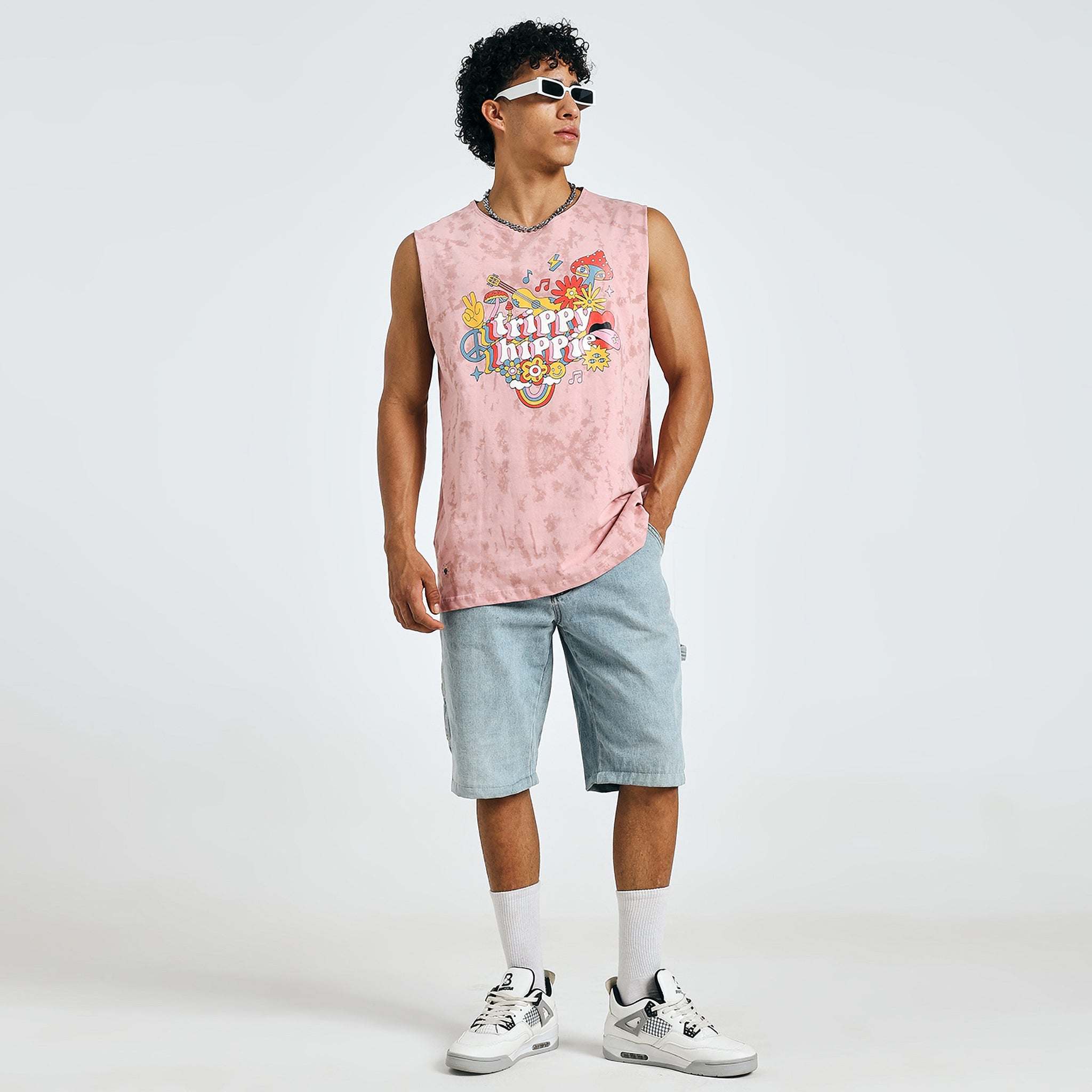 Man in pink “Trippy Hippie” tank top striking a fashion-forward pose with sunglasses