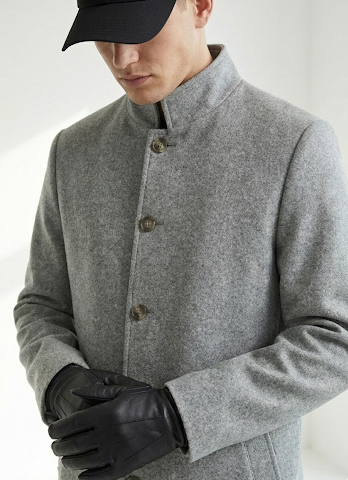 Man wearing a gray coat with black buttons and black gloves on a white background