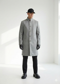 Person wearing a gray coat, black pants, and black shoes on a white background