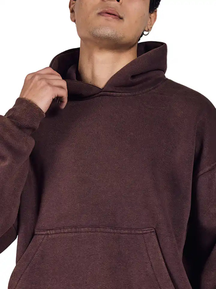 Person wearing a brown acid wash hoodie with a neutral background