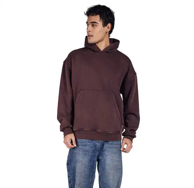 Man wearing a brown acid wash hoodie and blue jeans on a white background