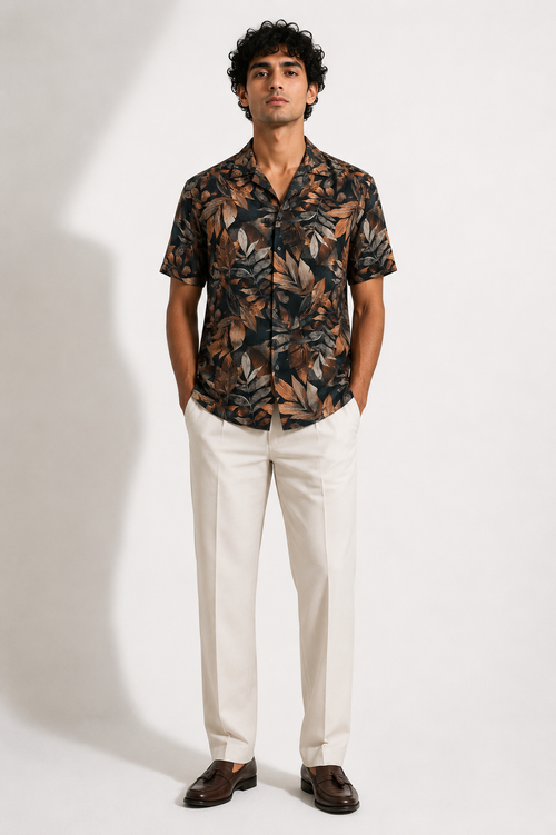 Man wearing a patterned shirt and white pants on a plain background