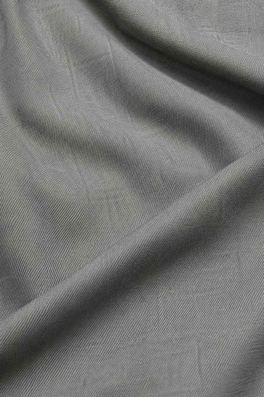 A close-up of draped gray fabric with a subtle woven texture and soft folds.