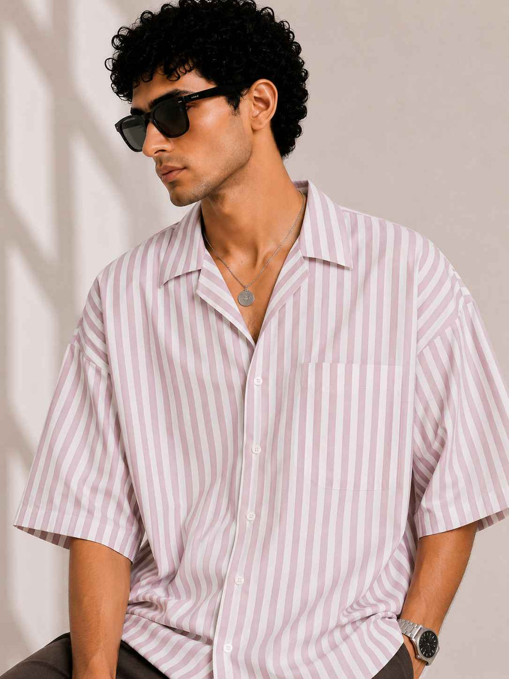 Man wearing a striped shirt and sunglasses against a neutral background