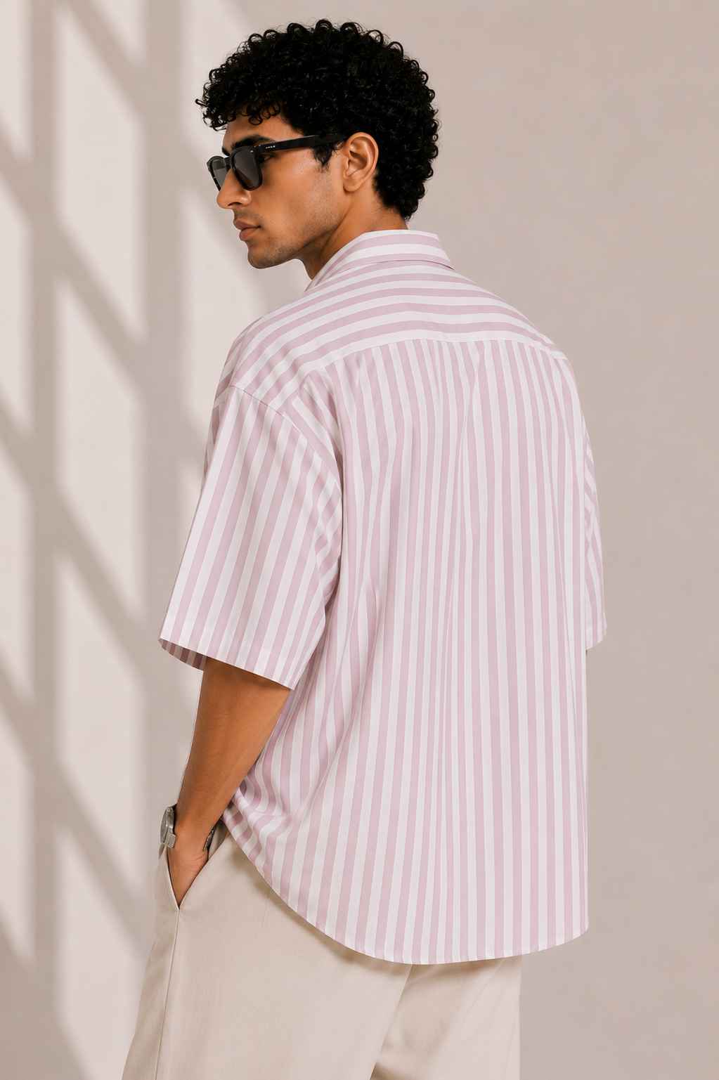 Person wearing a striped shirt and sunglasses against a neutral background