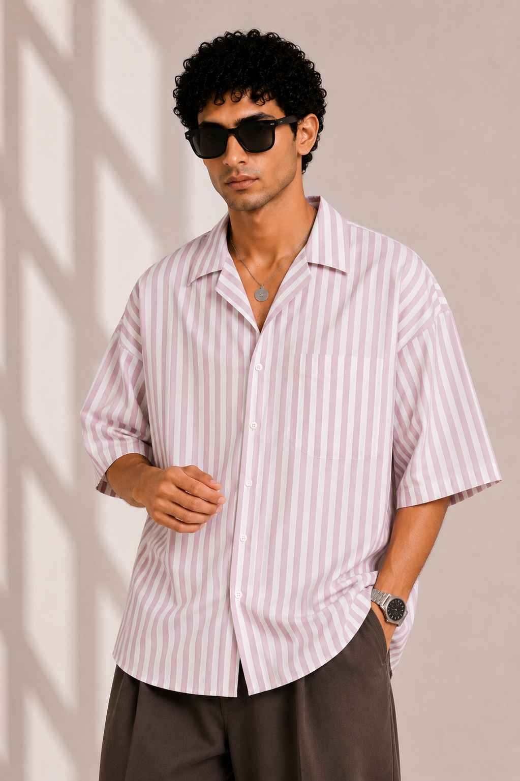 Man wearing a striped shirt and sunglasses against a beige background