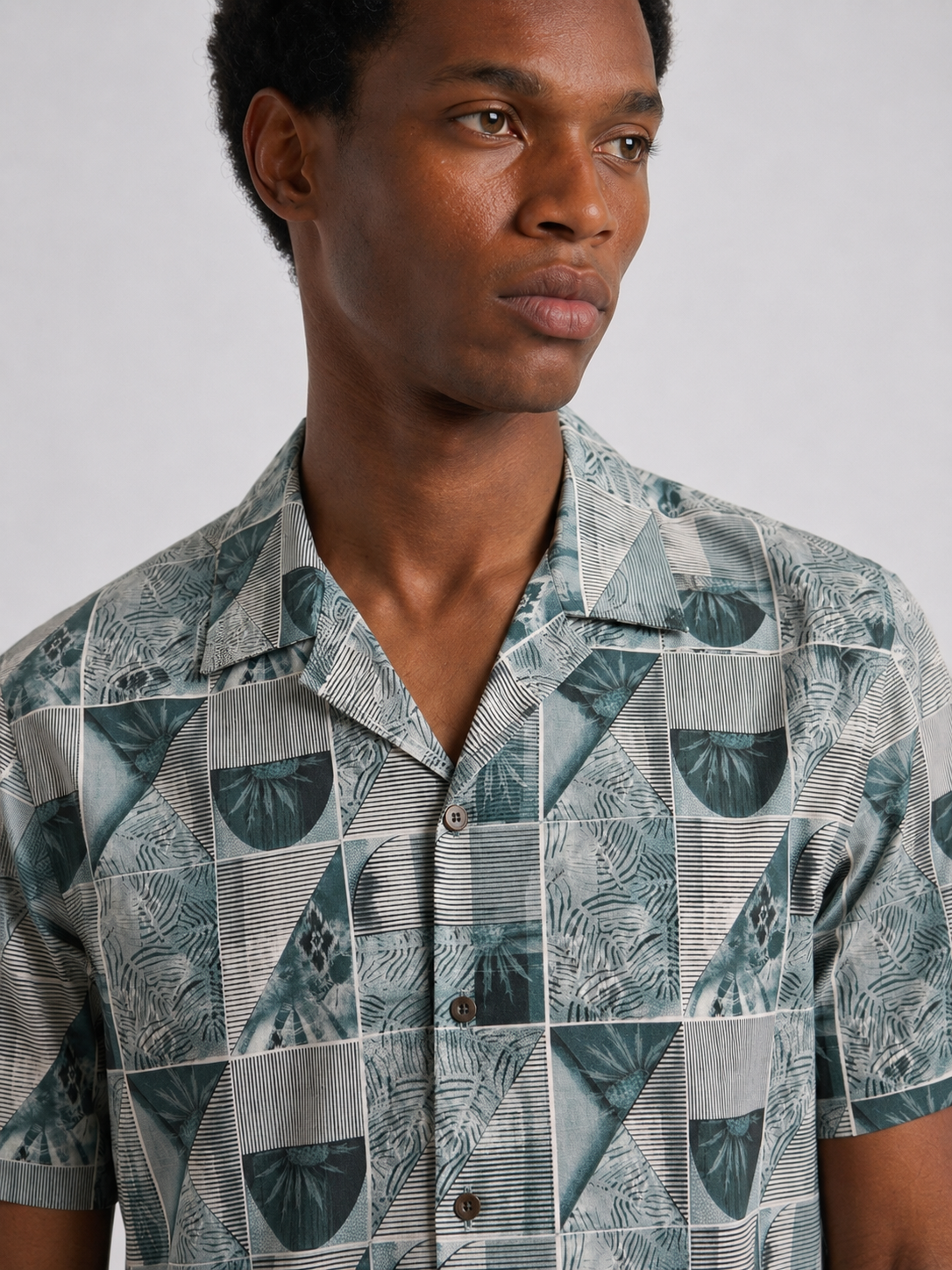 Man wearing a patterned shirt with a neutral background