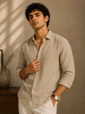Man wearing a beige shirt against a warm-toned wall