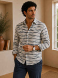 Man wearing a patterned shirt and dark pants indoors