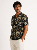 Man wearing a black floral patterned shirt on a white background