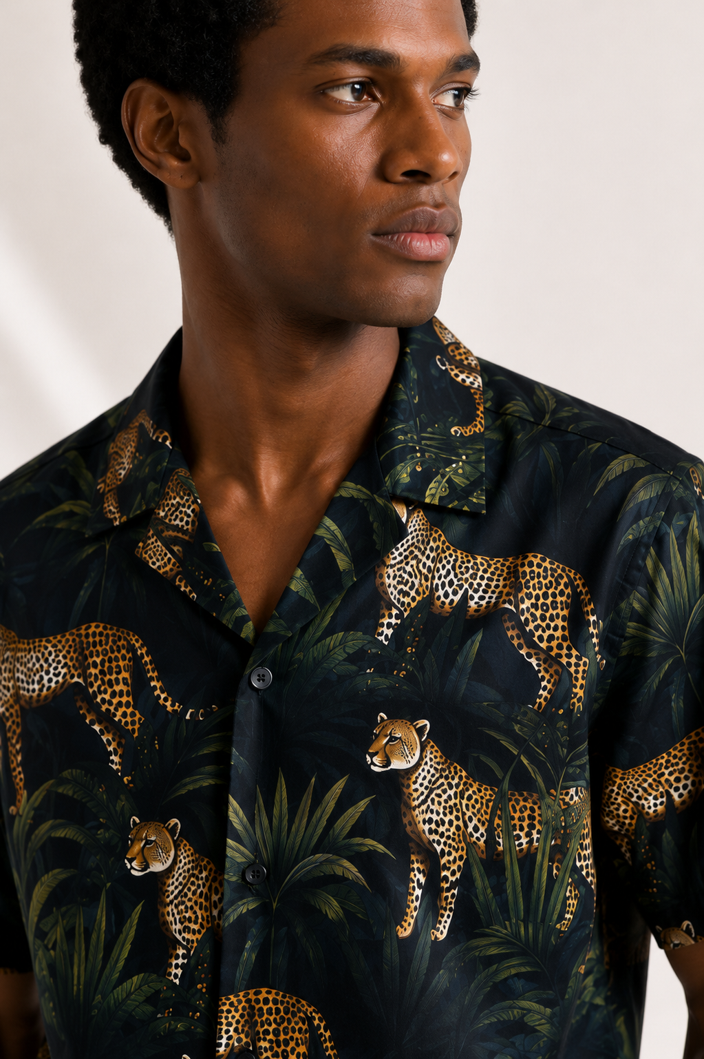Man wearing a dark shirt with a leopard print pattern against a plain background