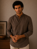 Man wearing a brown shirt standing against a neutral background