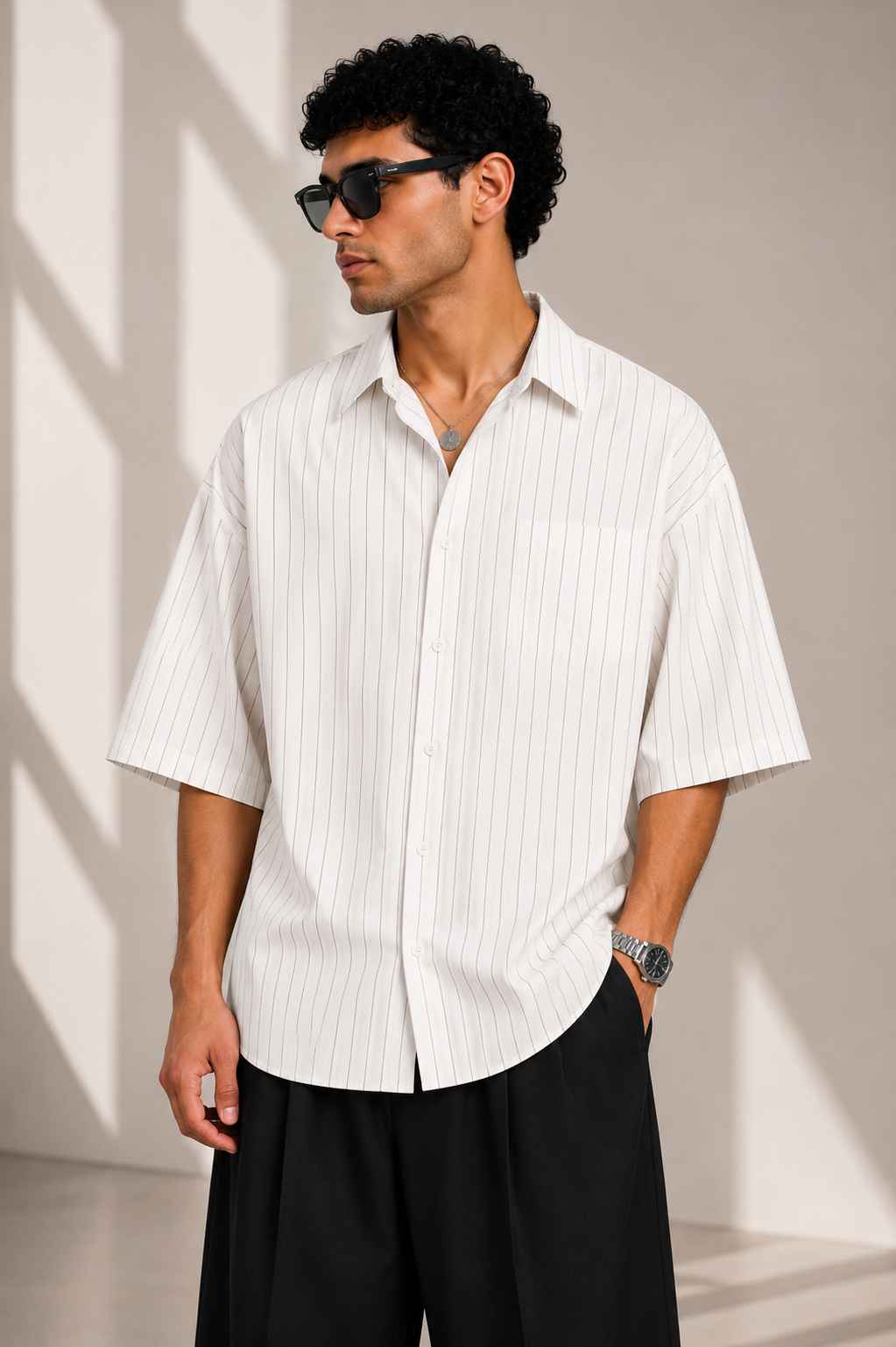 Man wearing a white striped shirt and black pants against a beige background