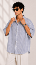 Man wearing a blue and white striped shirt with rolled-up sleeves against a plain background