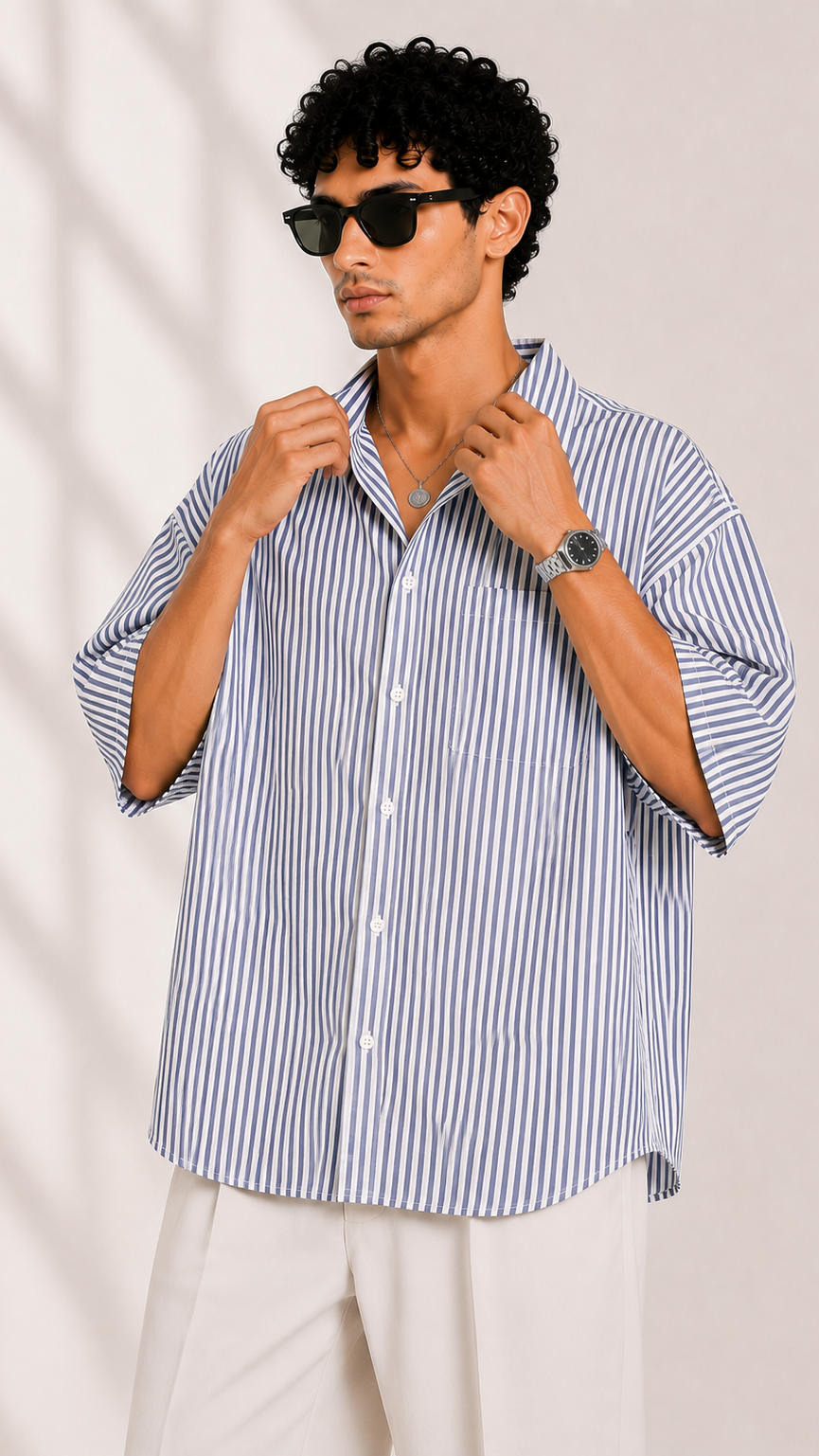 Man wearing a blue and white striped shirt with rolled-up sleeves against a plain background
