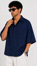 Man wearing a navy pinstripe shirt and sunglasses against a white background