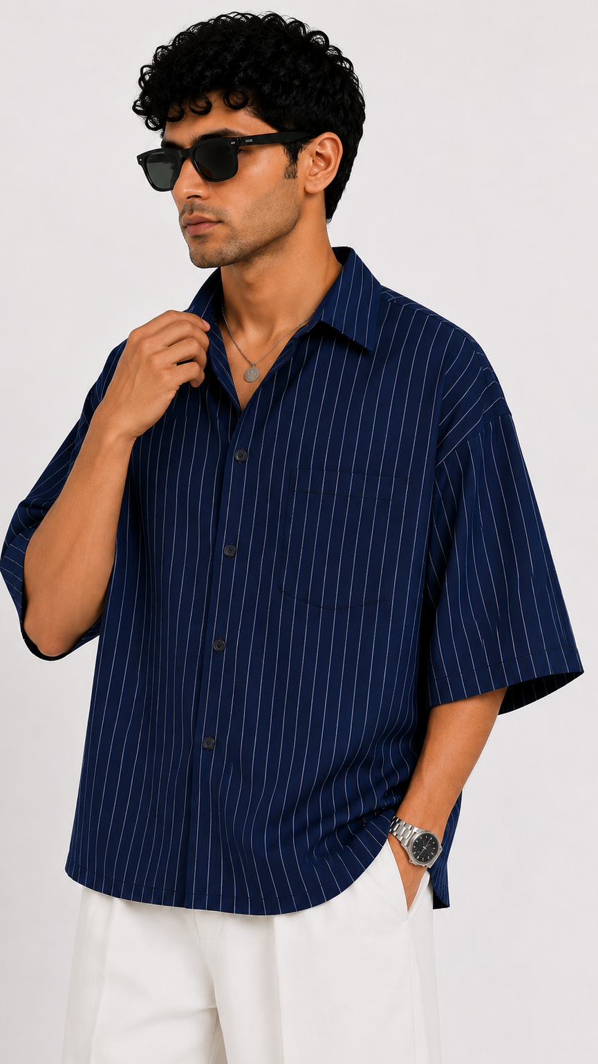 Man wearing a navy pinstripe shirt and sunglasses against a white background