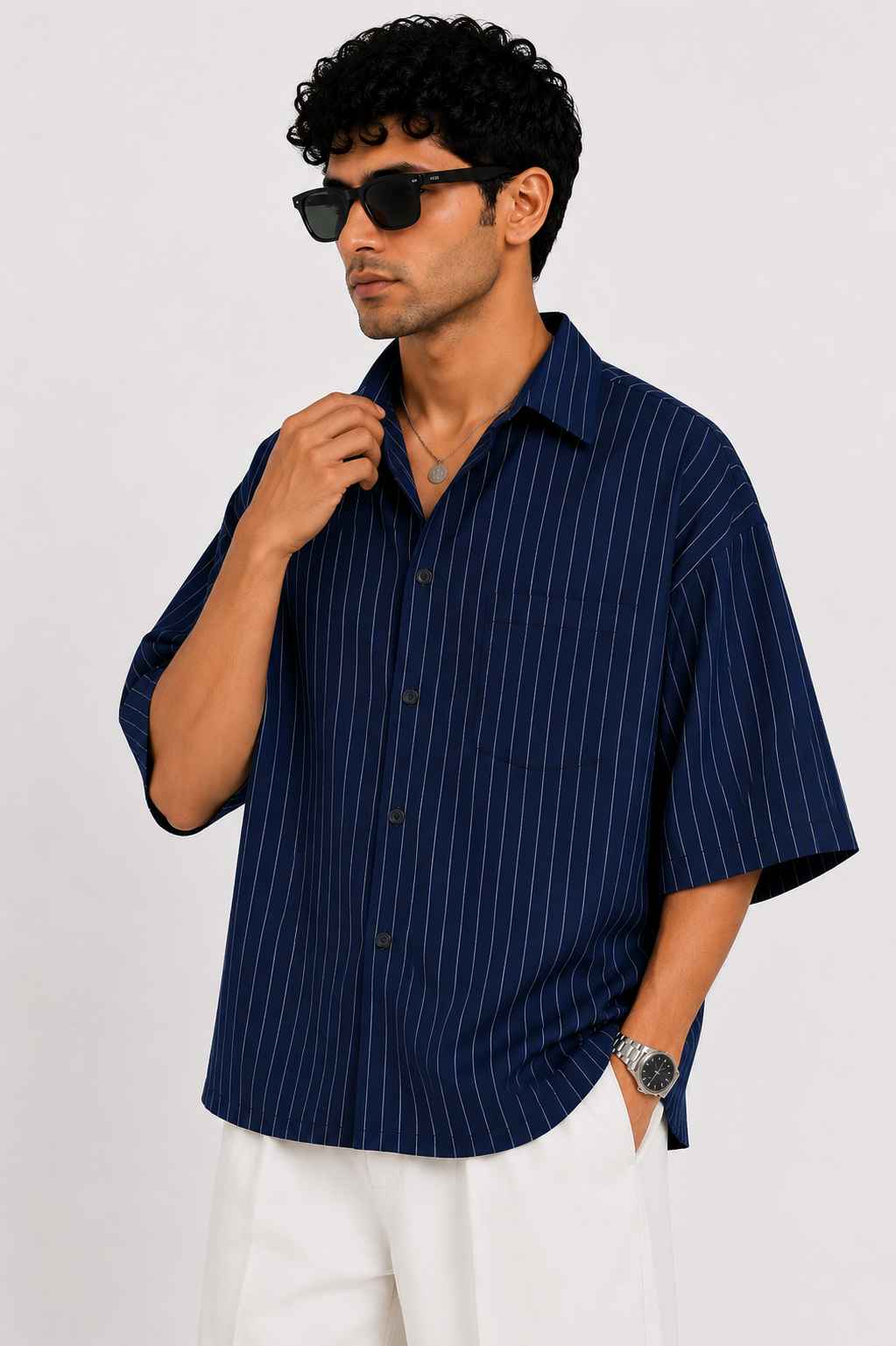 Man wearing a navy pinstripe shirt and sunglasses against a white background