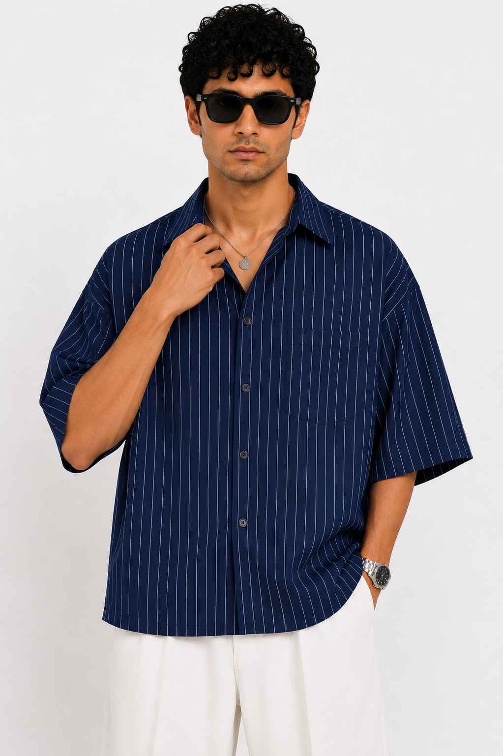 Man wearing a navy striped shirt and sunglasses against a white background