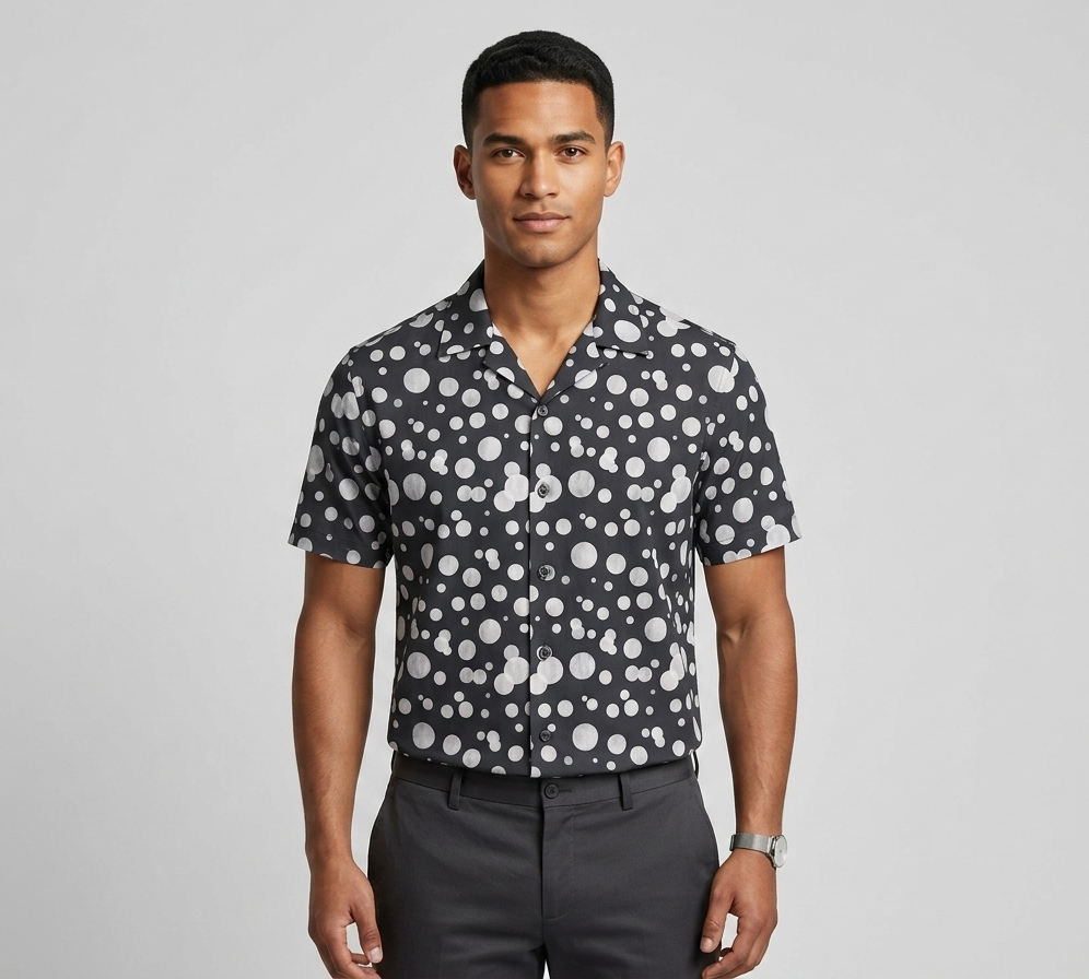 Man wearing a black shirt with white polka dot pattern on a gray background