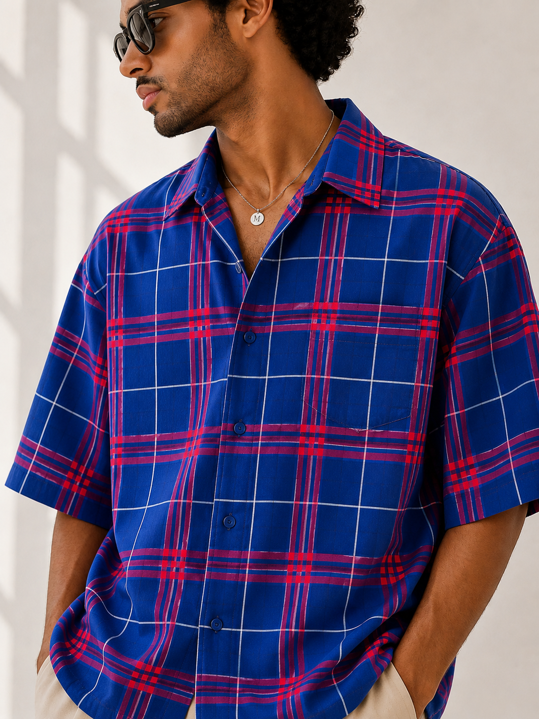 Man wearing a blue and red plaid shirt against a white background