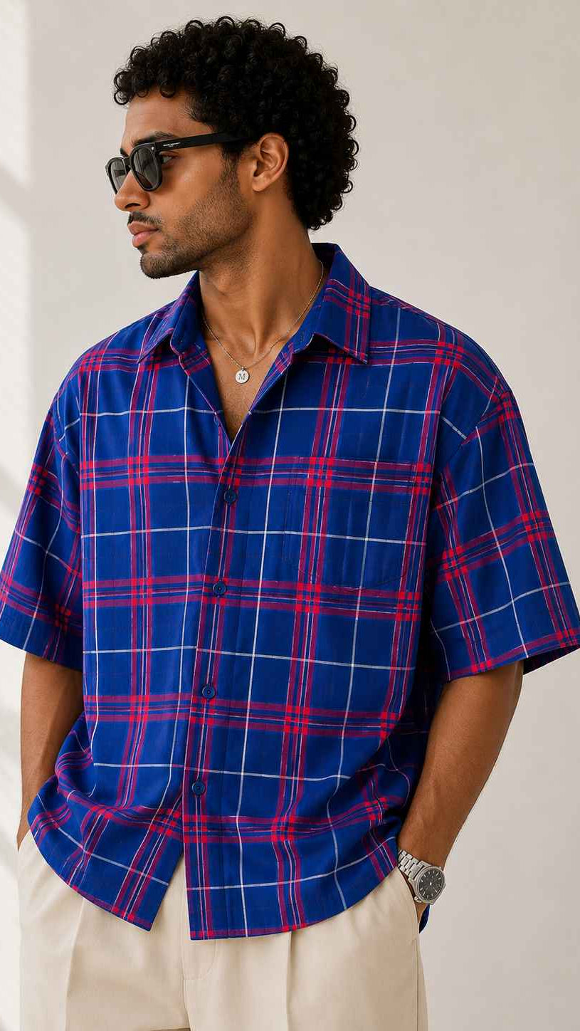 Man wearing a blue and red plaid shirt with sunglasses indoors.