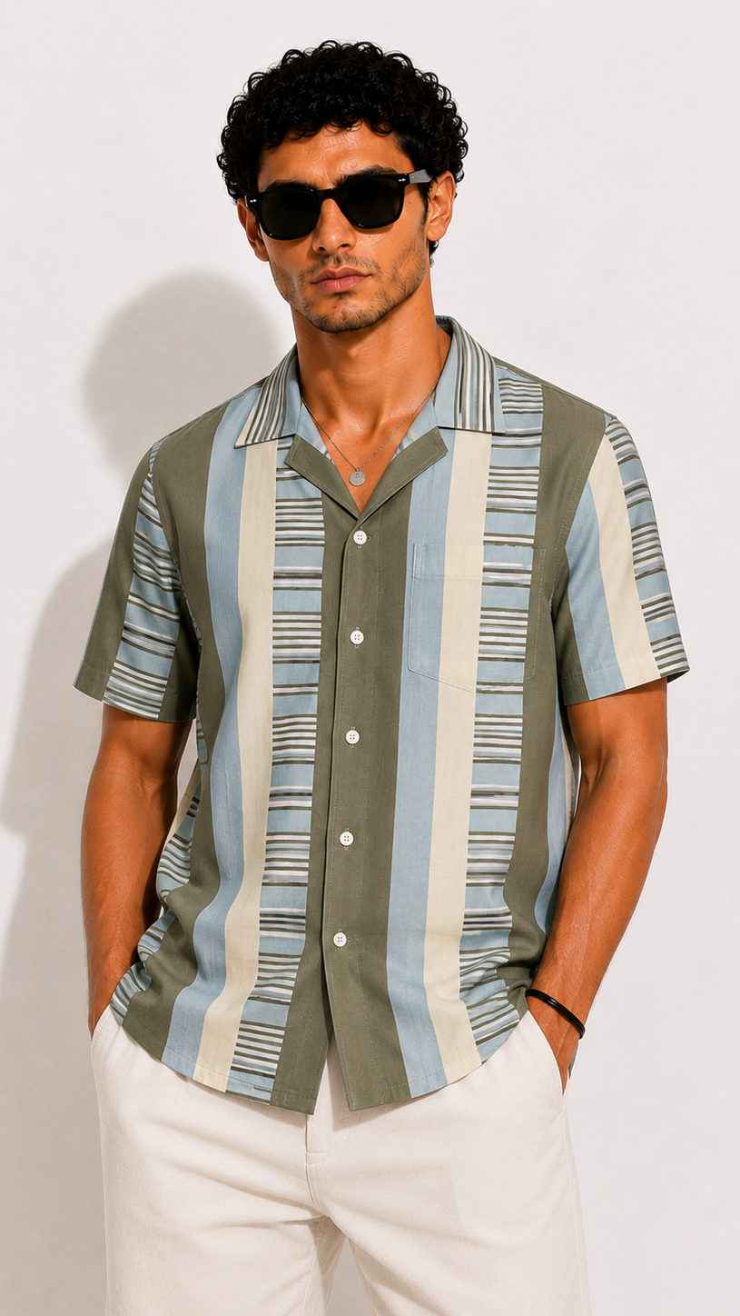 Man wearing a patterned shirt and sunglasses against a plain background