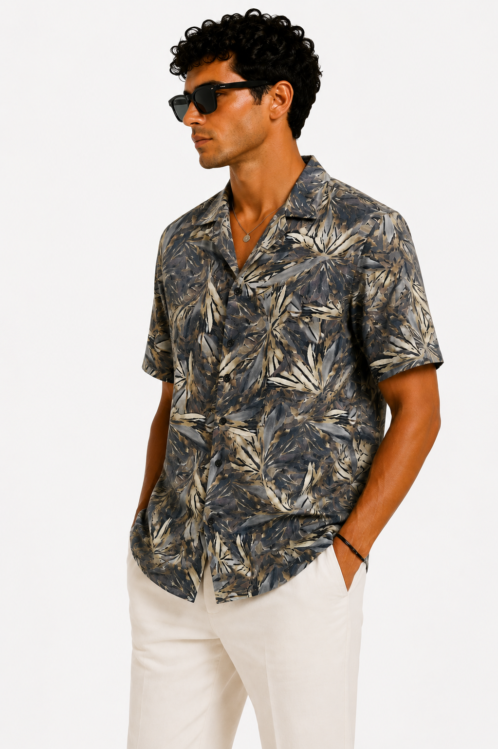 Man wearing a patterned shirt and sunglasses on a white background