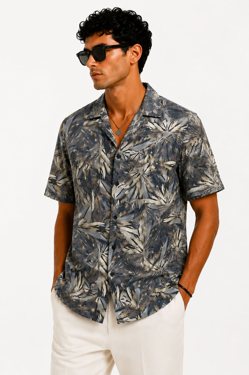 Man wearing a patterned shirt and sunglasses on a white background