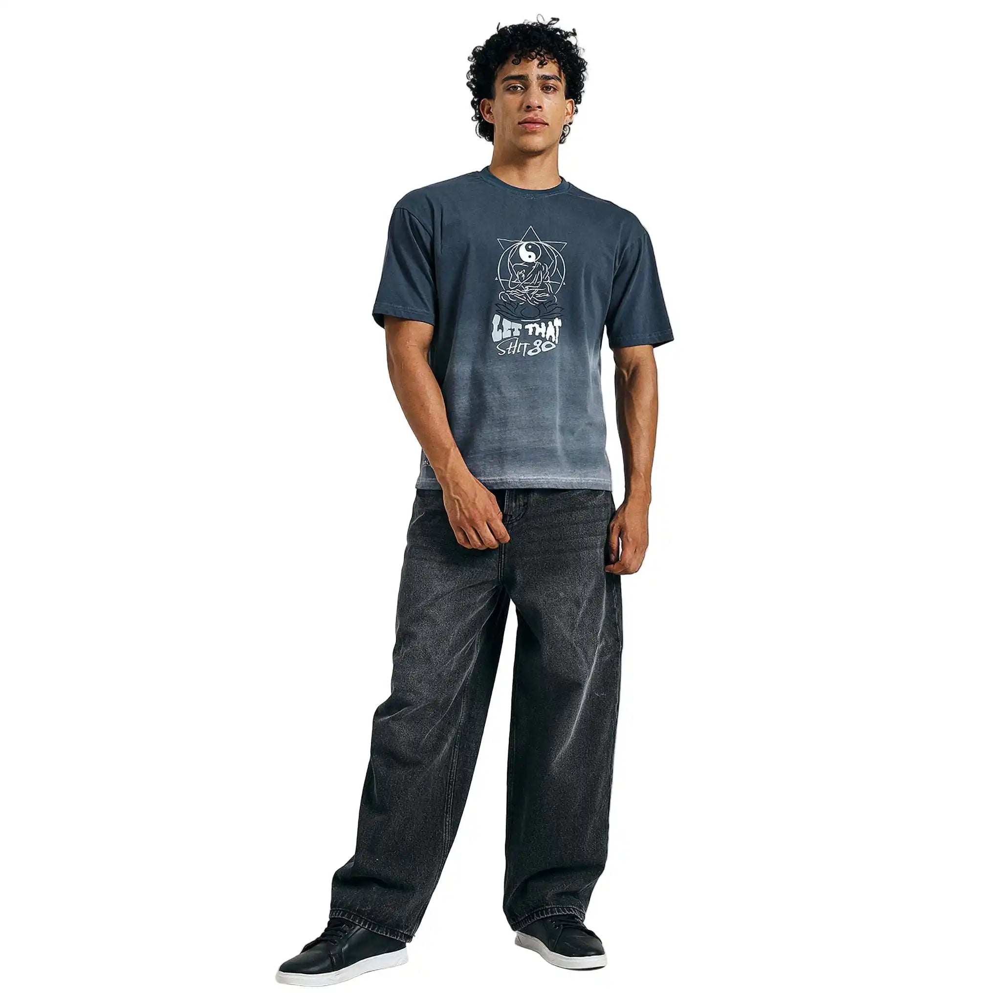 Man wearing a blue t-shirt with a graphic design and text, standing against a plain background