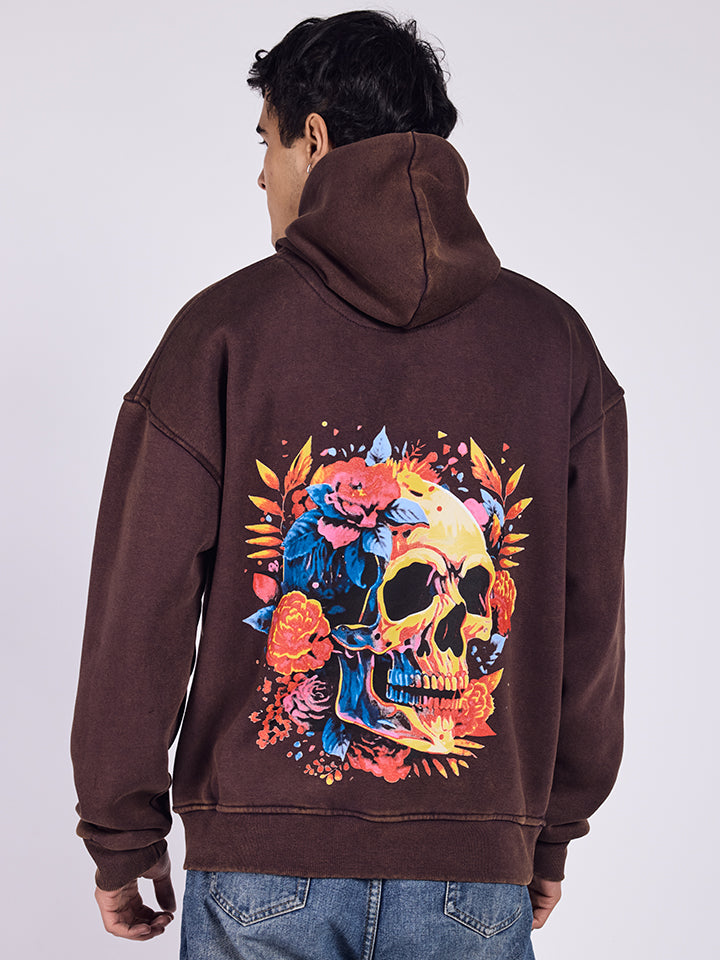 A hoodie with a flowery skull print on the back, in a rust color.