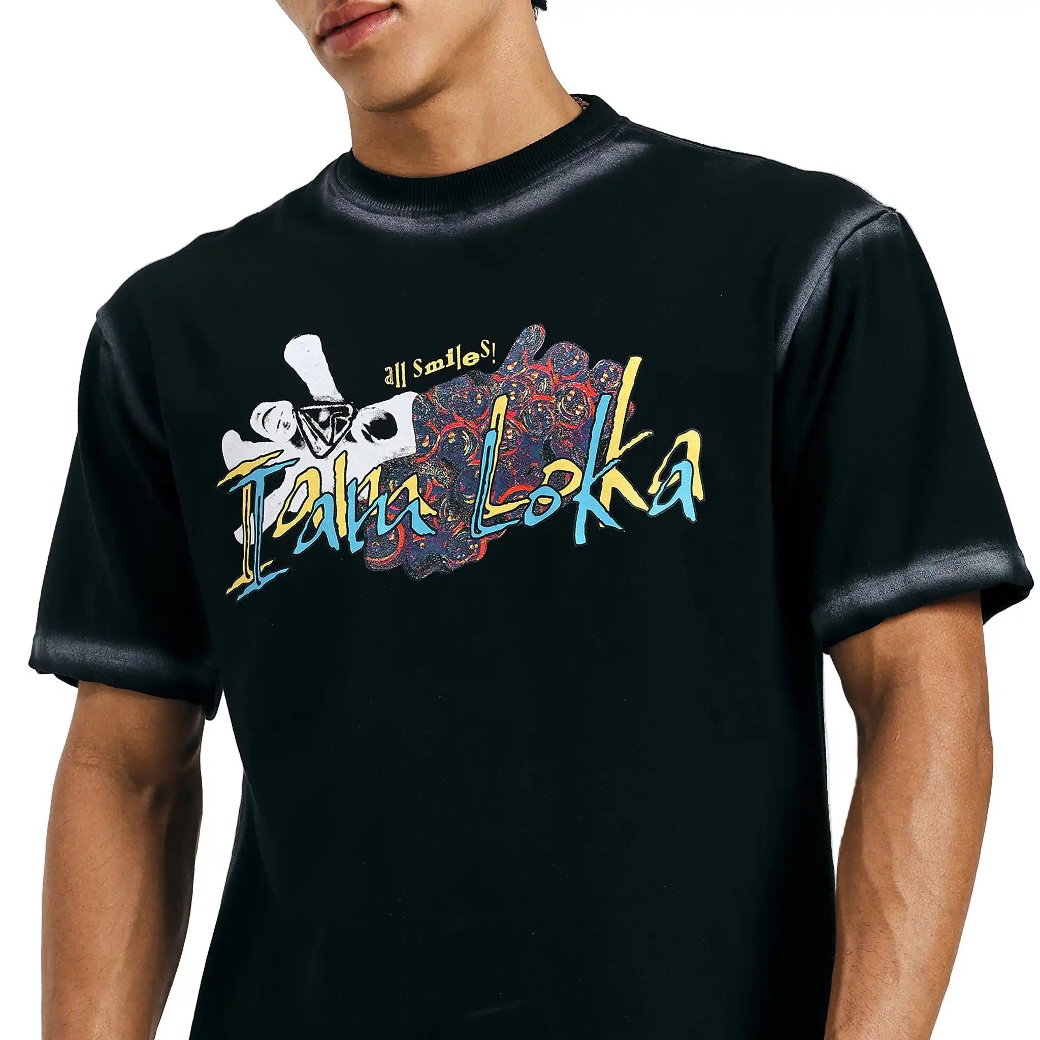 A person wearing a black T-shirt with a vibrant multicolored design featuring a white skull, text 'Iamloka', and colorful abstract patterns.