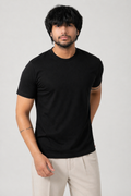 Man wearing a black t-shirt and light-colored pants on a plain background