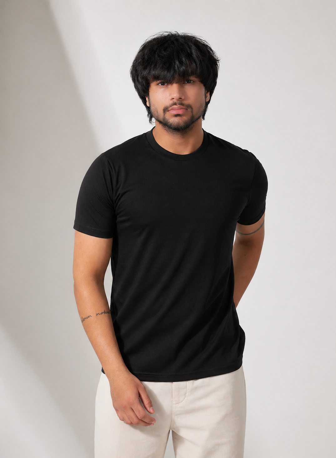 Person wearing a black t-shirt and white pants against a plain background