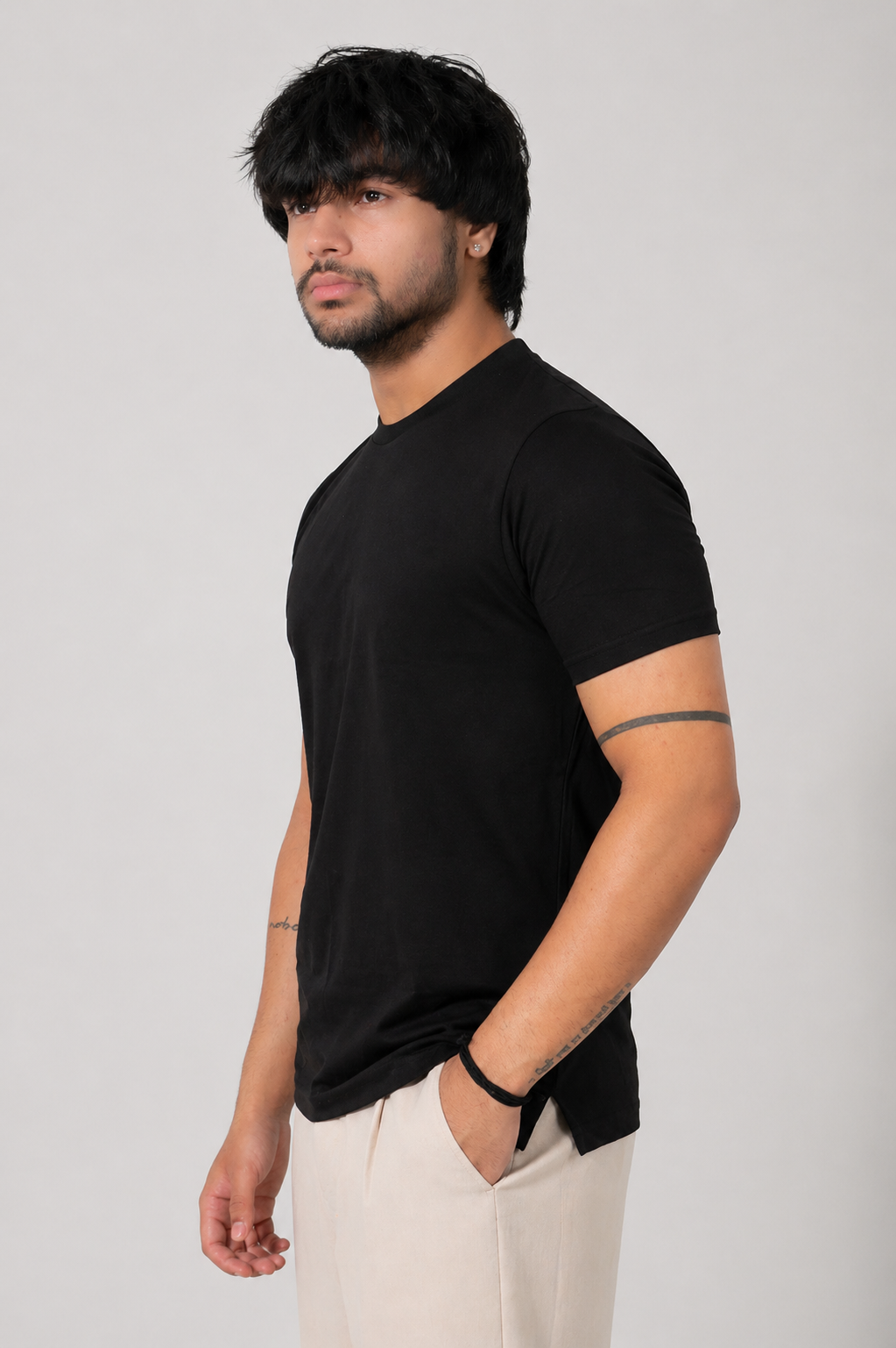 Man wearing a black t-shirt and white pants against a plain background