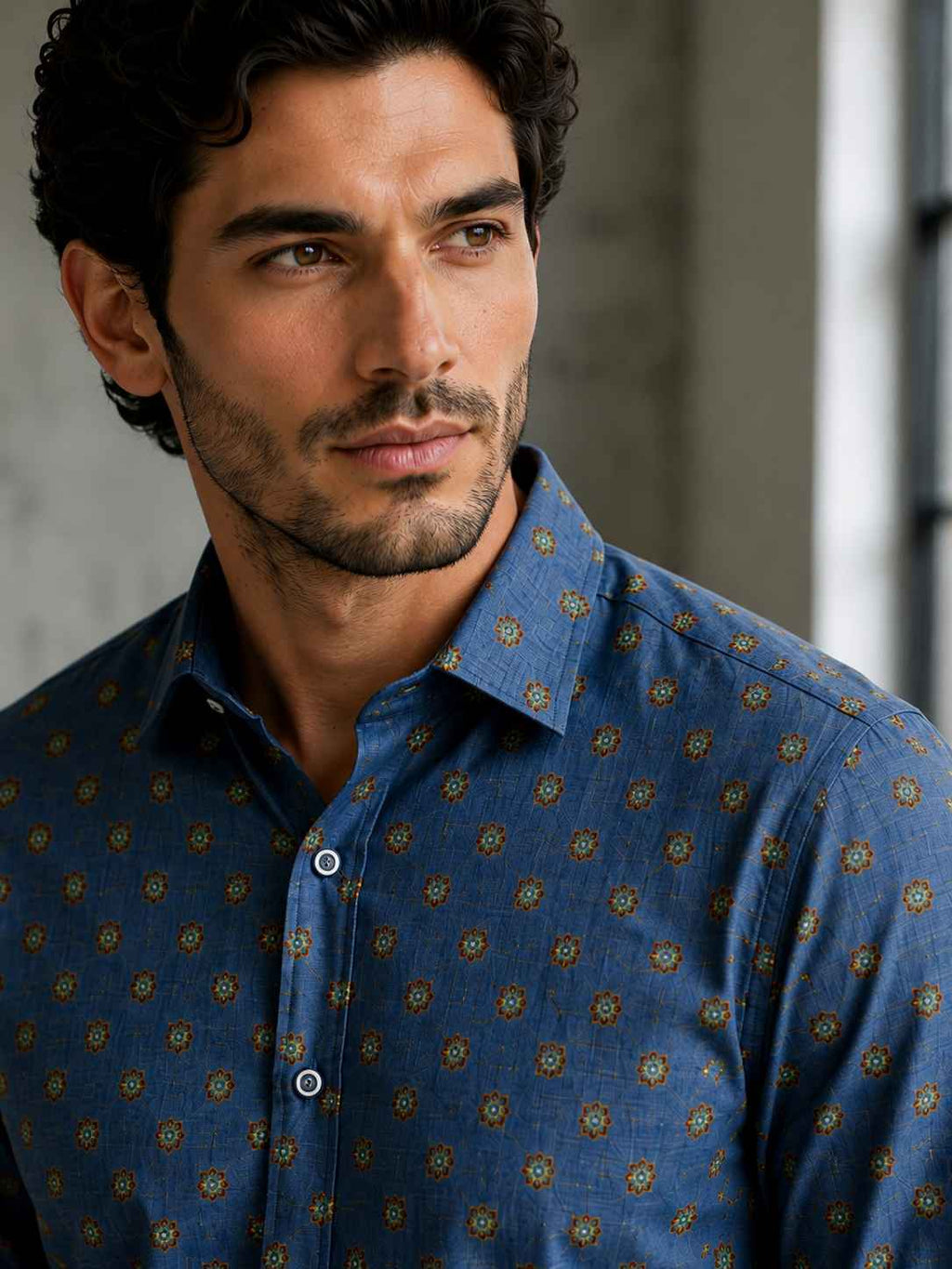 Man wearing a blue patterned shirt against a neutral background