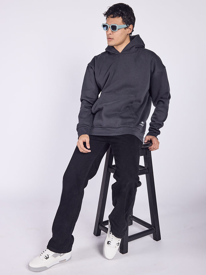 A person wearing a dark gray hoodie with the text 'Puff Puff Pass' at back on it, paired with black pants and white shoes.