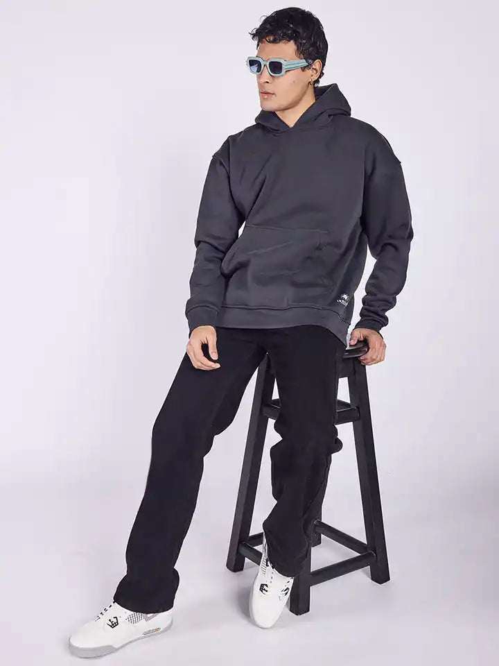 A person wearing a dark gray hoodie with the text 'Puff Puff Pass' at back on it, paired with black pants and white shoes.
