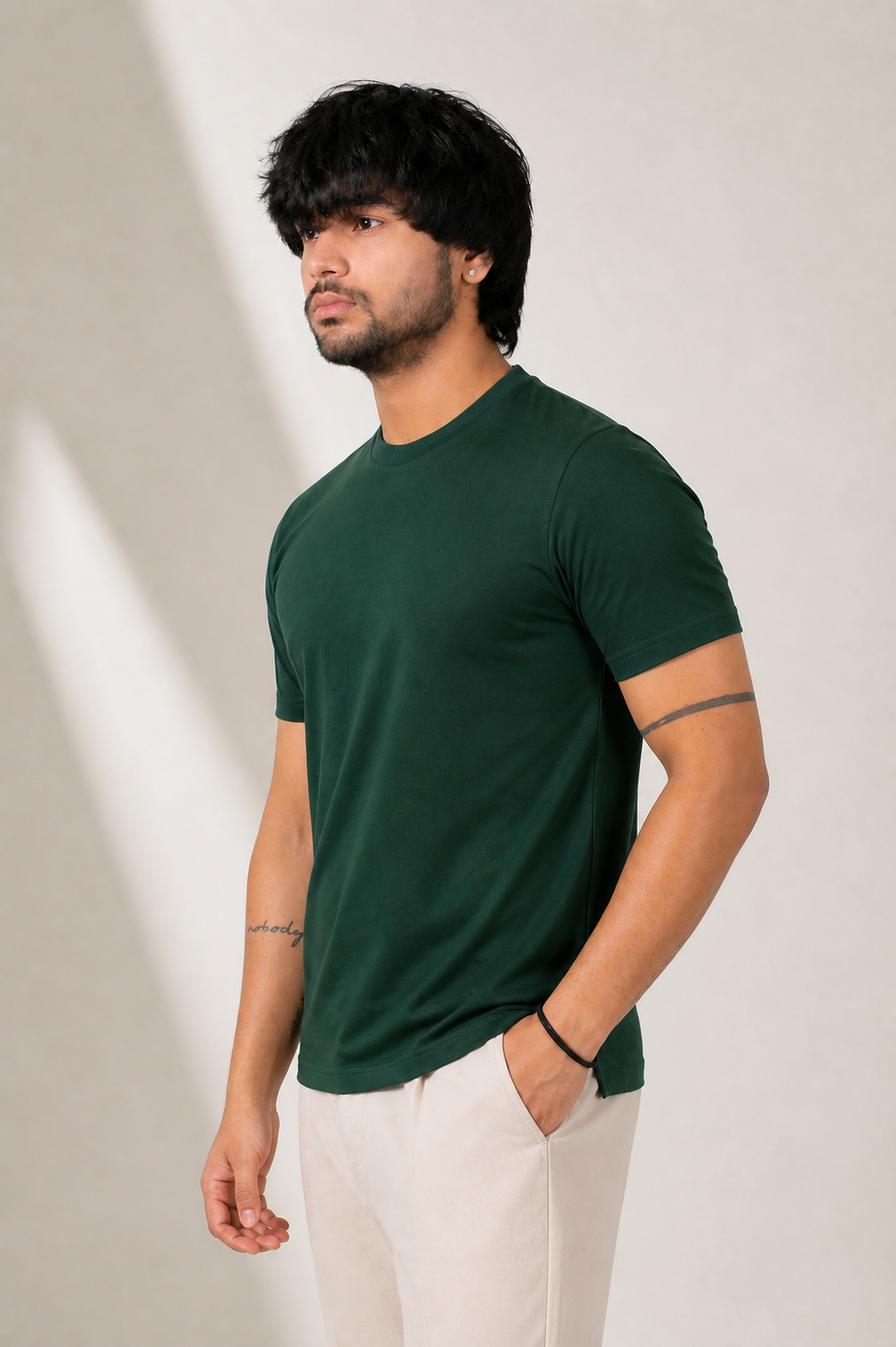Man wearing a green t-shirt and white pants against a neutral background