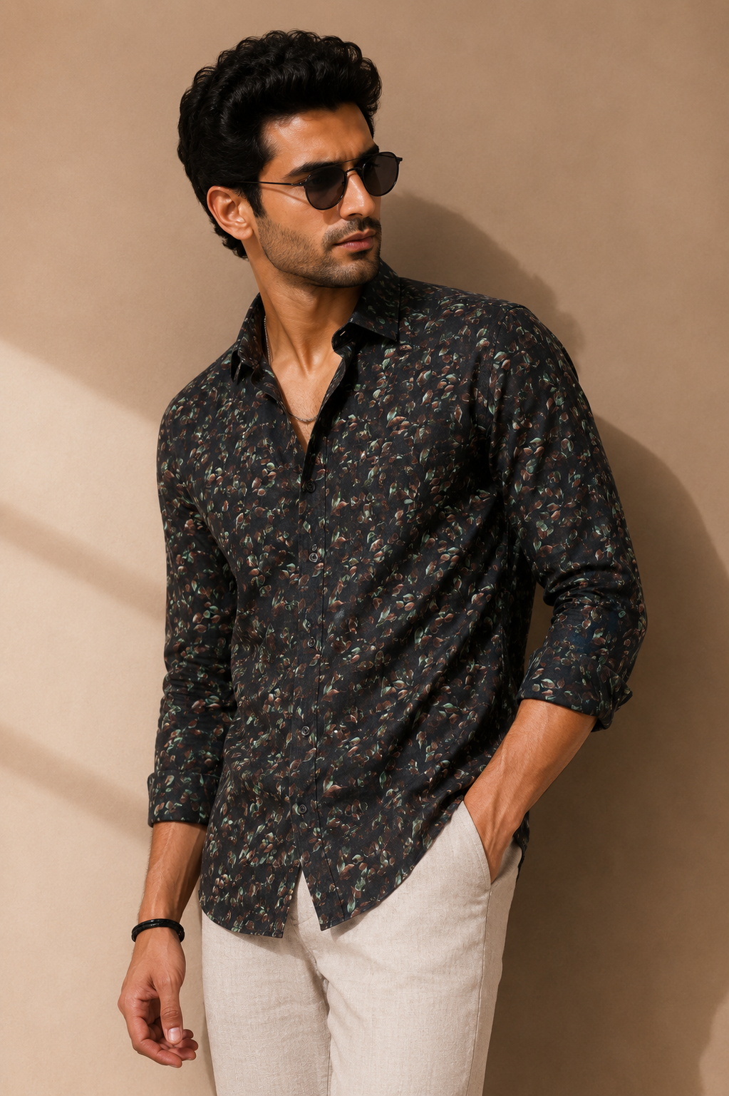 Man wearing a dark floral shirt and sunglasses against a beige background