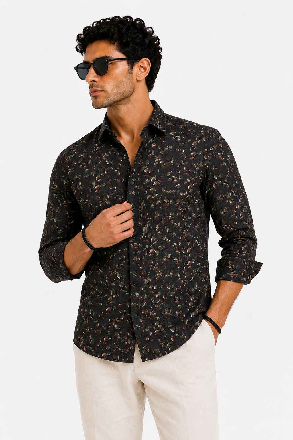 Man wearing a black patterned shirt and sunglasses on a white background