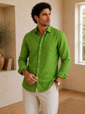 Man wearing a green shirt and white pants in a room with a window and plant.