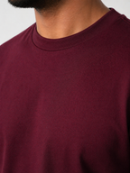 Close-up of a person wearing a burgundy sweater with a neutral background