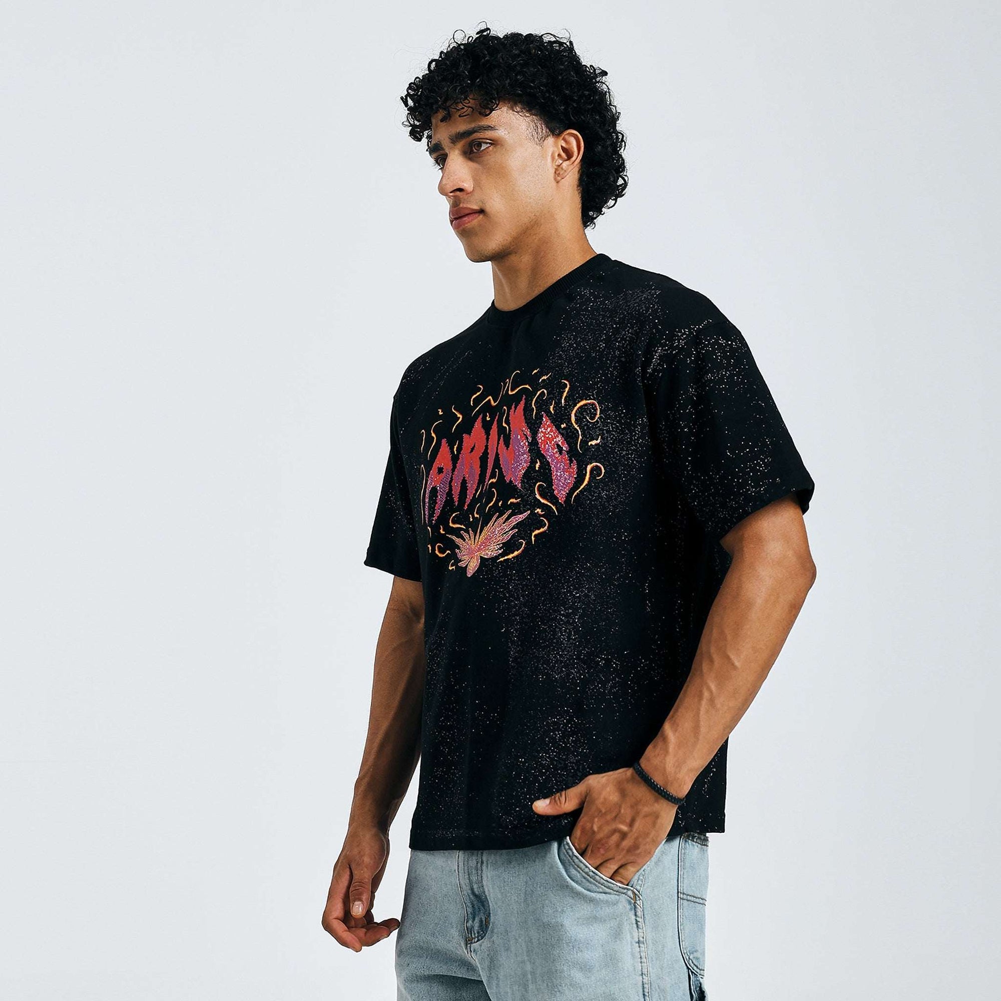 Black Arise graphic tee, side view, on model with hands in pockets