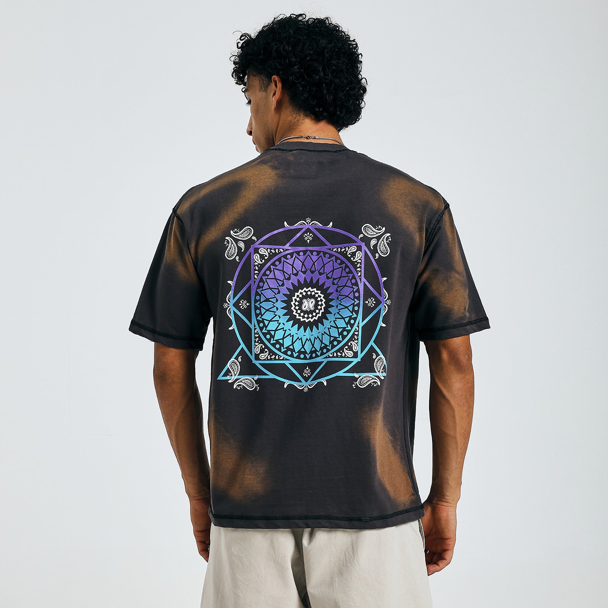 Buy black tie-dye tee with colorful mandala design, back view, paired with beige shorts.