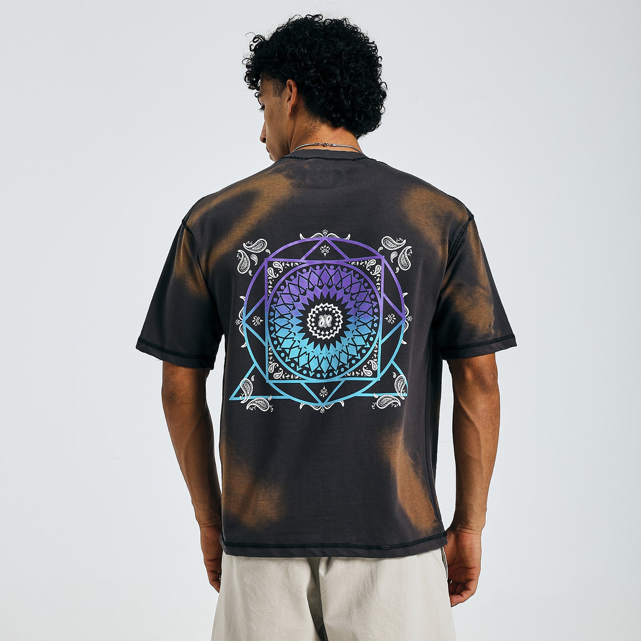Buy black tie-dye tee with colorful mandala design, back view, paired with beige shorts.