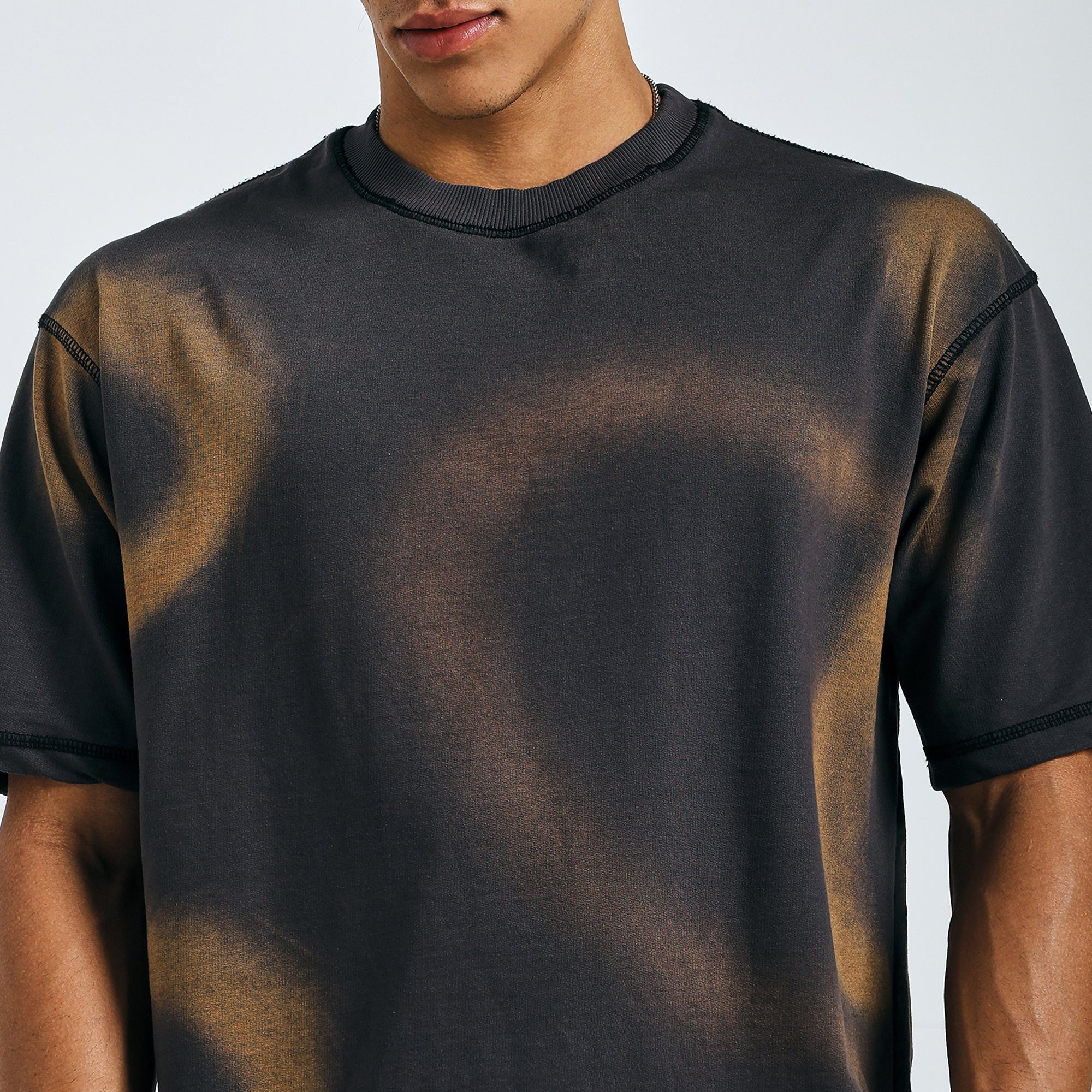 Close-up of black tie-dye mandala tee with subtle brown spray wash effect on chest.