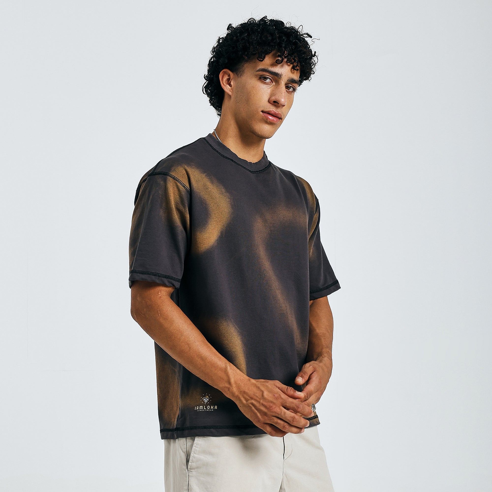 Buy black tie-dye mandala tee, front view, hands clasped, with beige shorts on model.